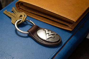 West Virginia Mountaineers Oval Leather Key Fob. Split Ring and Durable Stitching. Perfect Collegiate Key Chain Gift. Brown or Black Leather